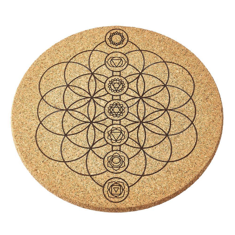 Round cork crystal grid with chakra symbol design on a white background