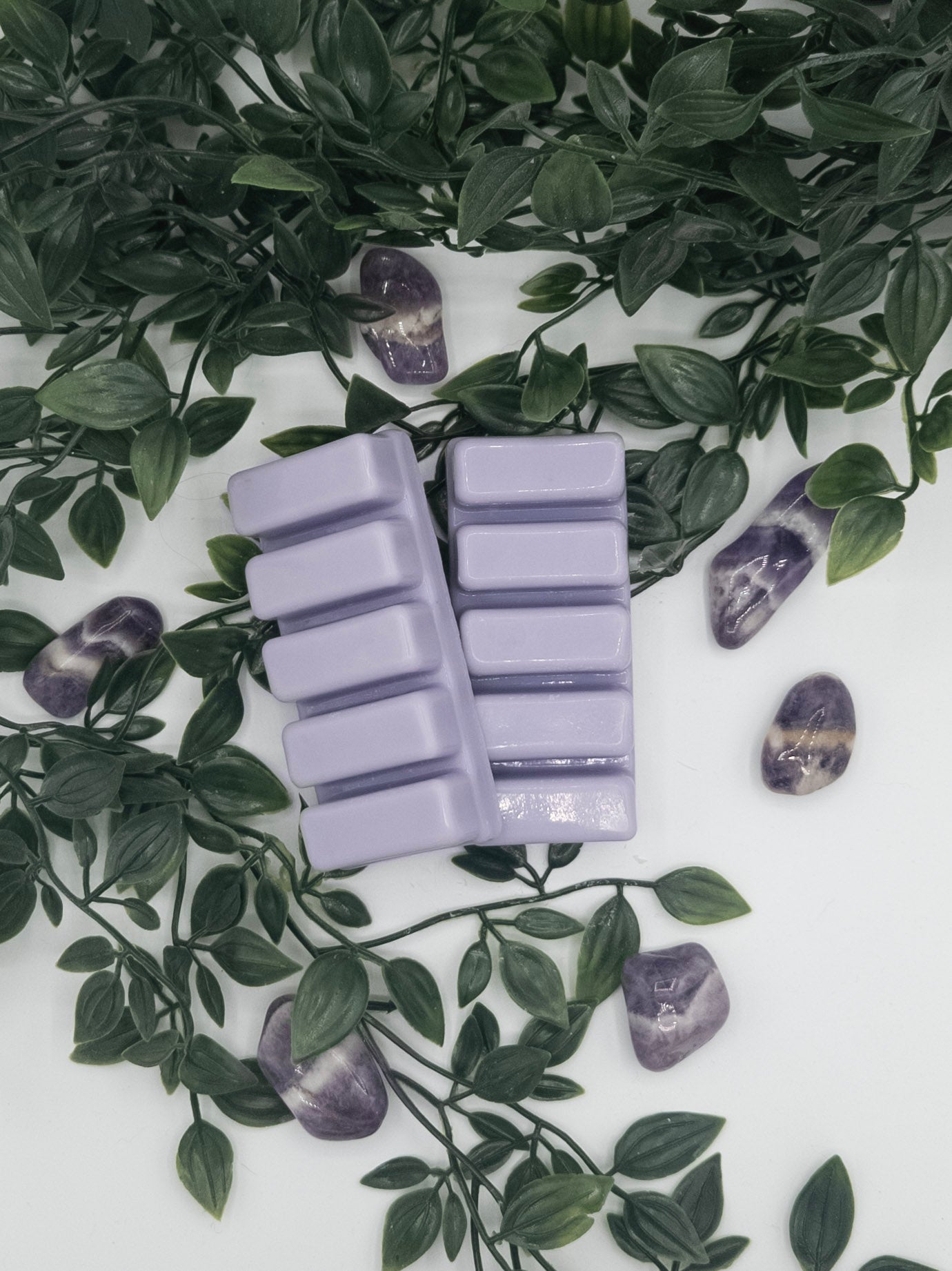 Purple wax melts on a white surface with green leaves