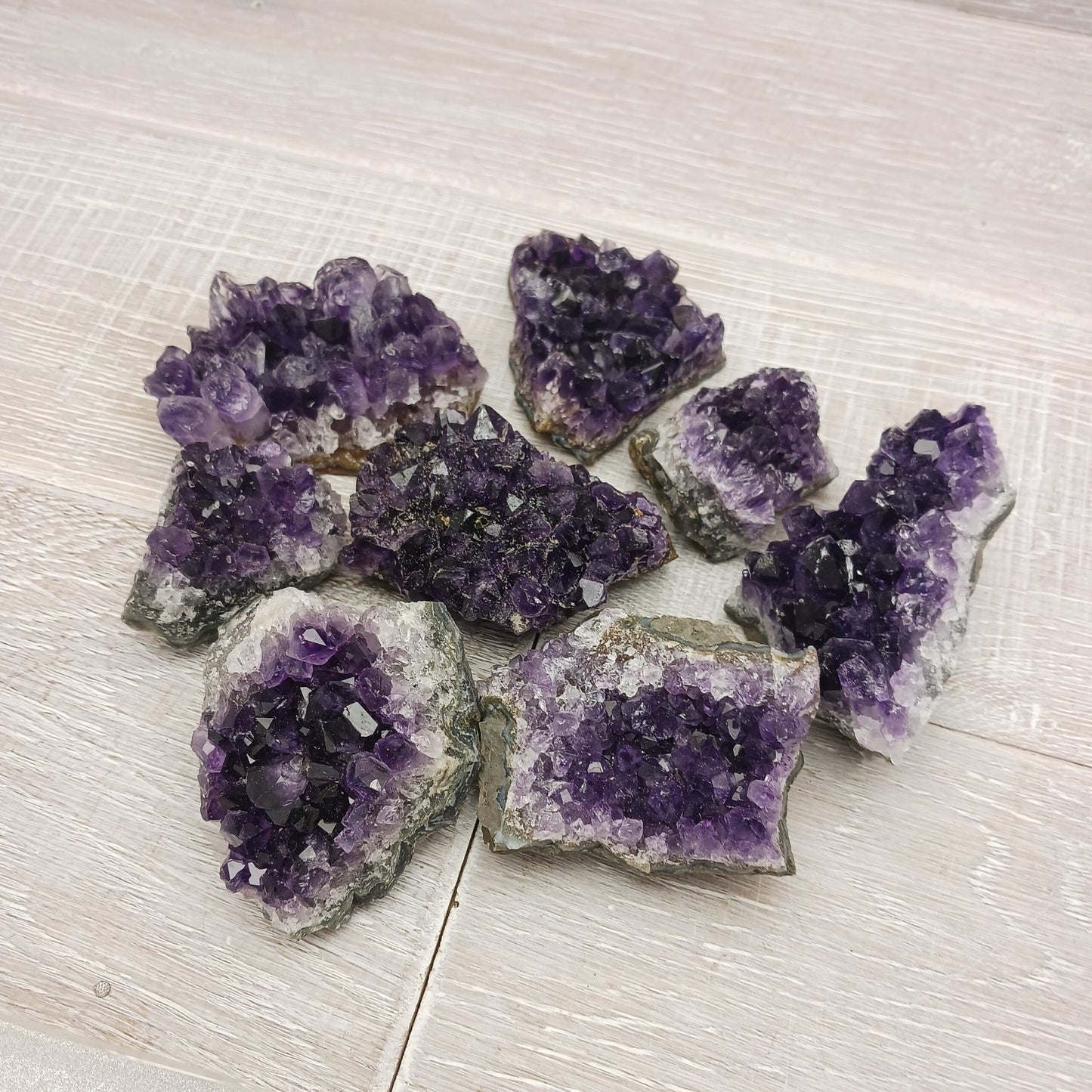Raw Amethyst crystal clusters on a light wooden surface