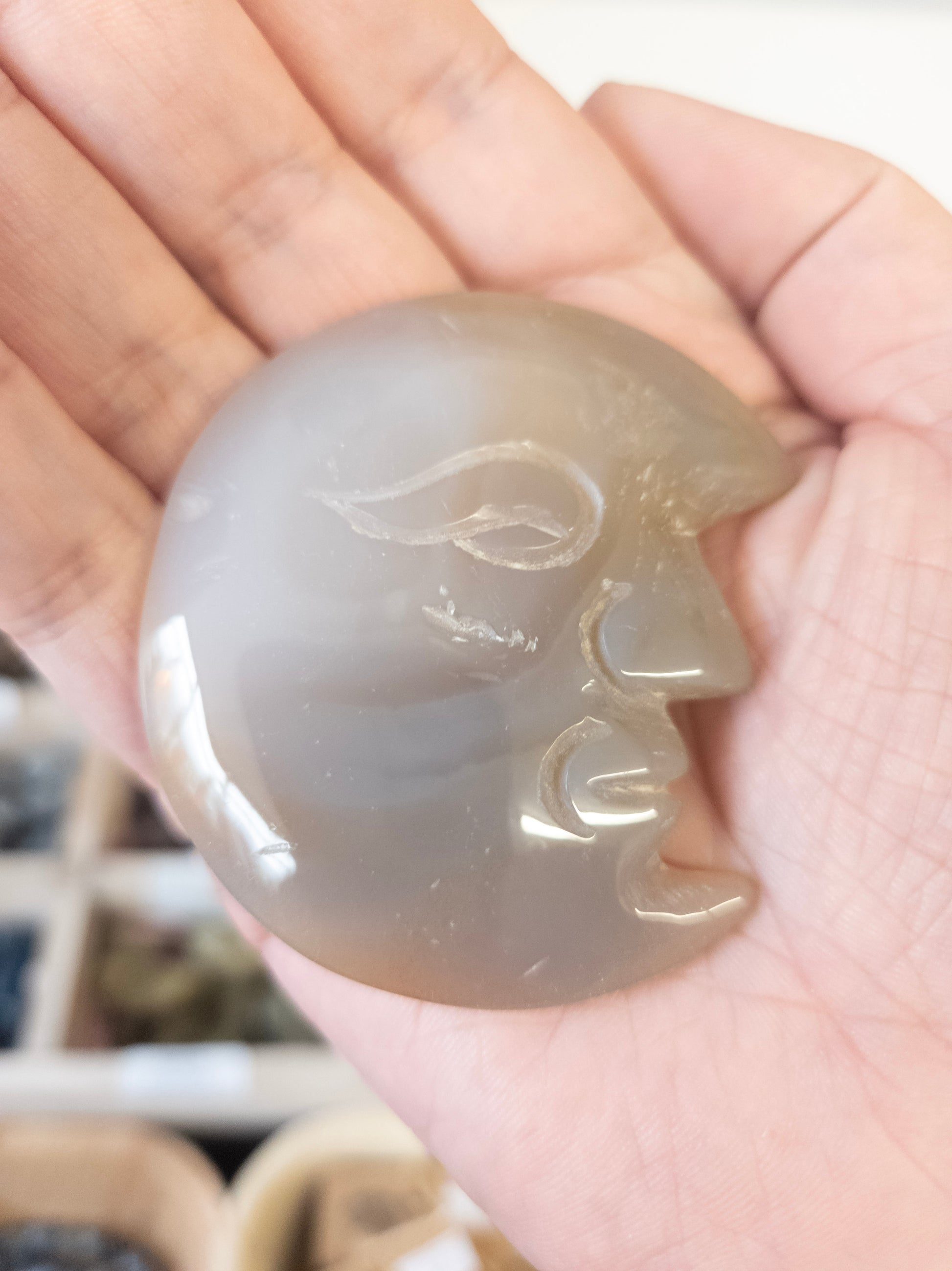 Hand holding a Agate moon shape stone with intricate carvings.