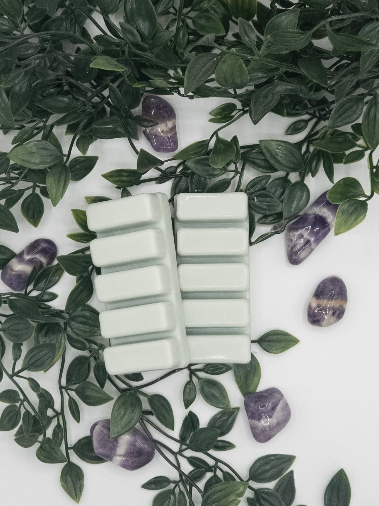Rectangular wax melts on a white surface with green leaves and Amethyst stones