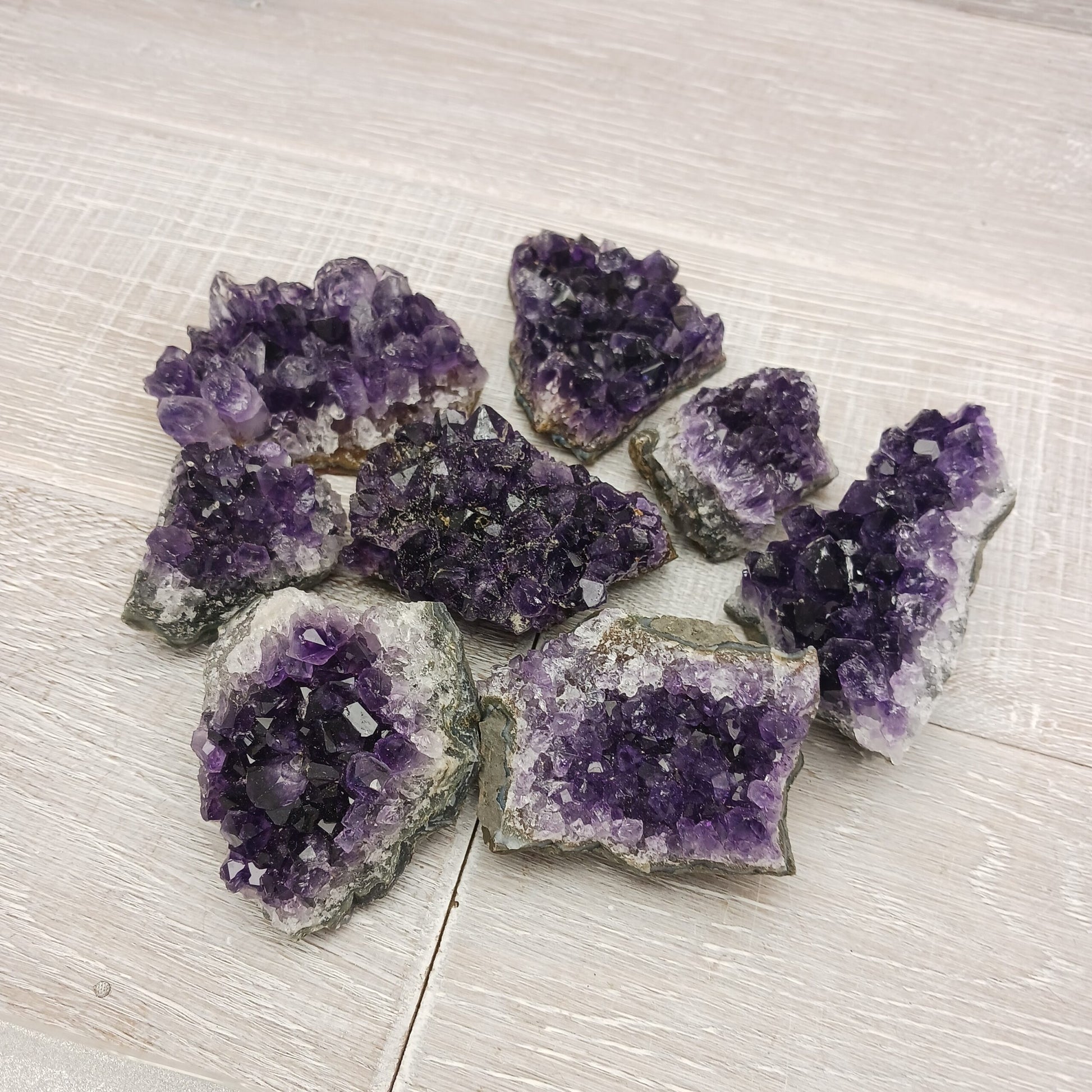 Raw Amethyst crystal clusters on a light wooden surface