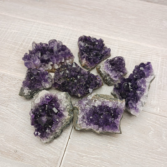 Raw Amethyst crystal clusters on a light wooden surface