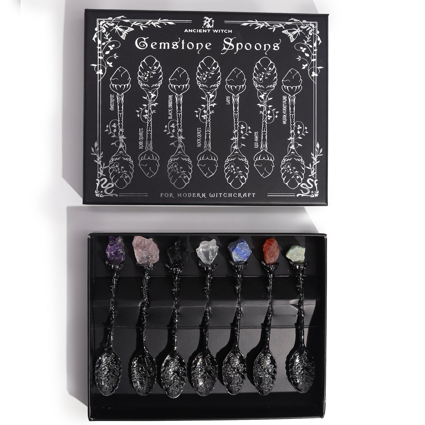 Set of gemstone spoons in a black box with decorative design and text.