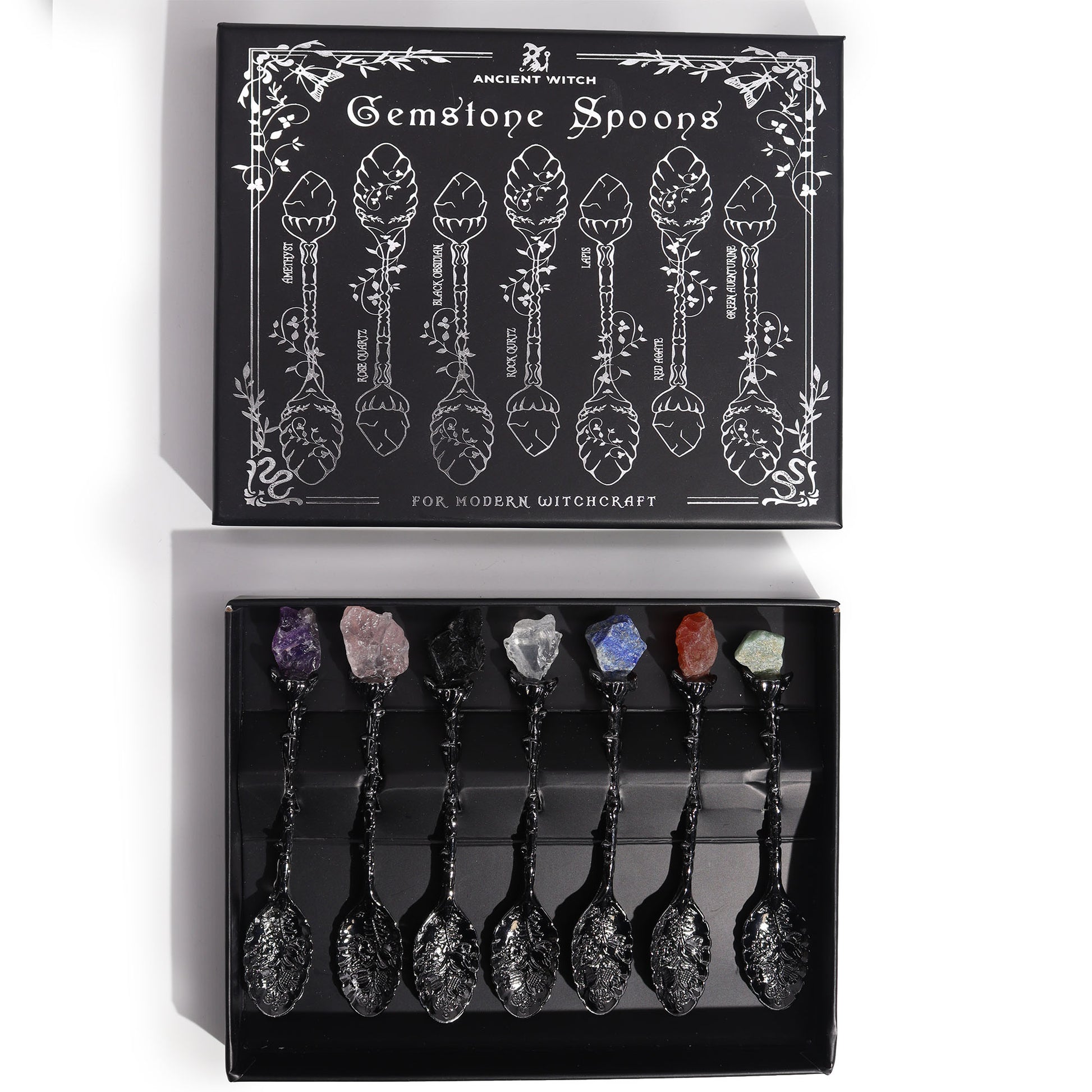 Set of gemstone spoons in a black box with decorative design and text.
