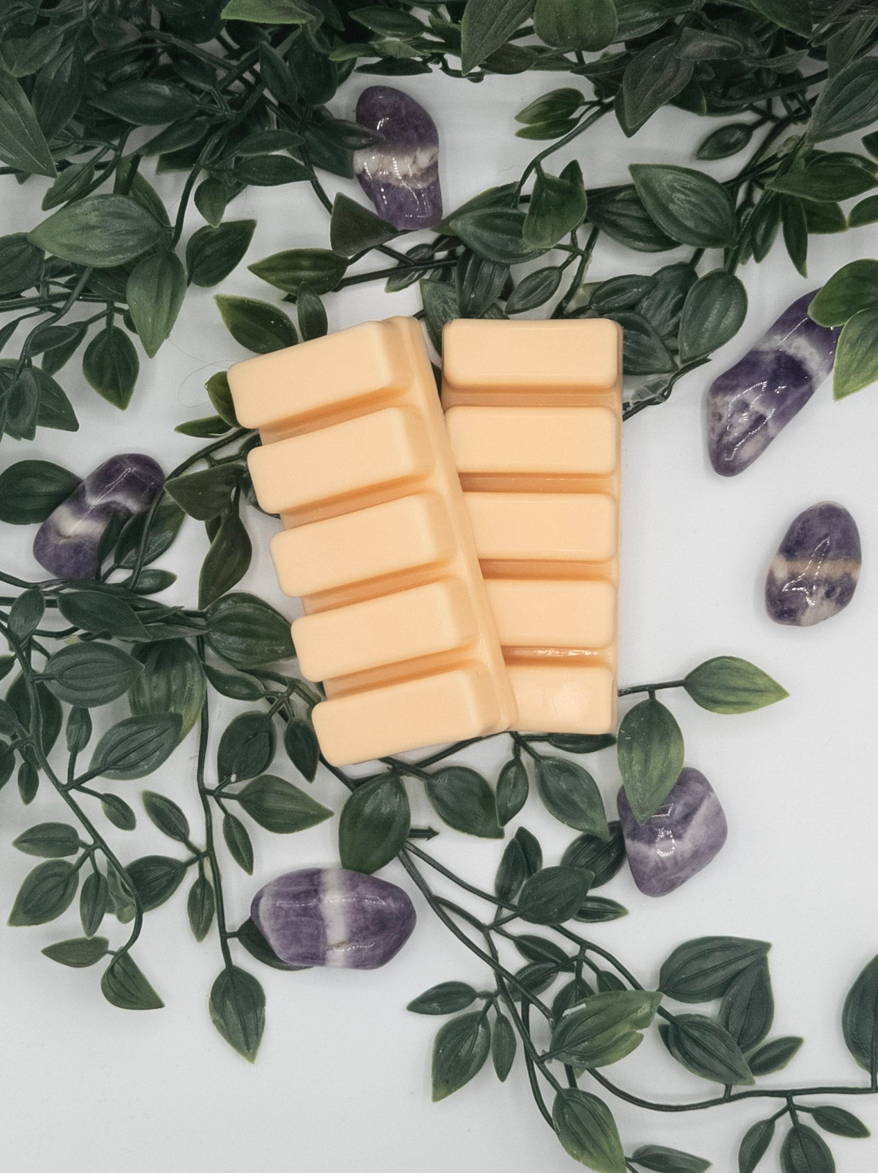 Wax melt snap bars on a white surface with green leaves and Amethyst stones