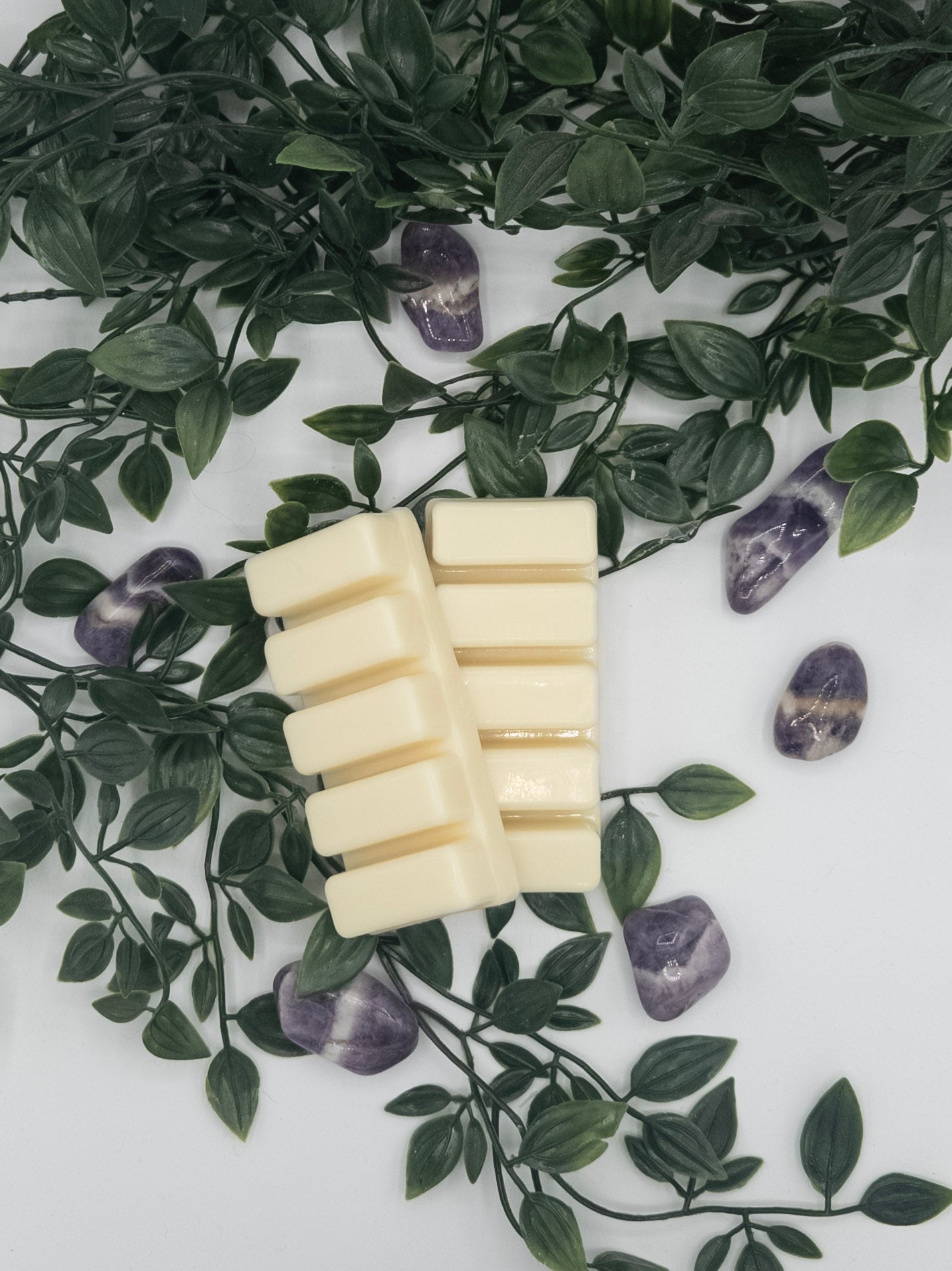 Stack of white snap bars on a white surface with green leaves and Amethyst stones