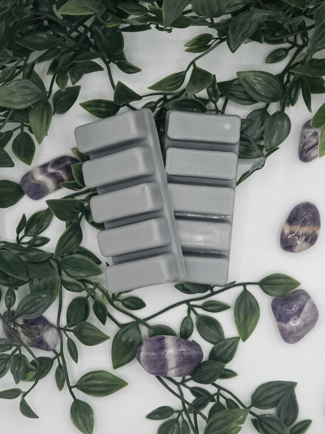 Gray snap bars on a white surface with green leaves and Amethyst stones.